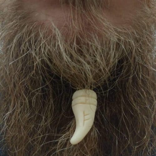 Custom beard jewelry in a tooth shape made from ivory.